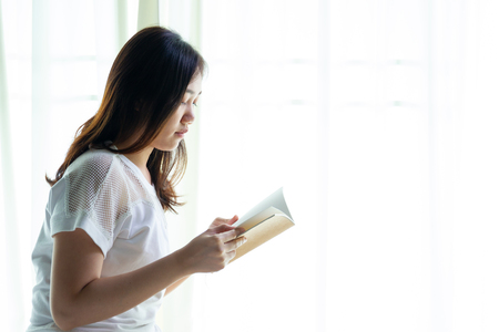 Asian women reading a book in a bedroom close up.の写真素材