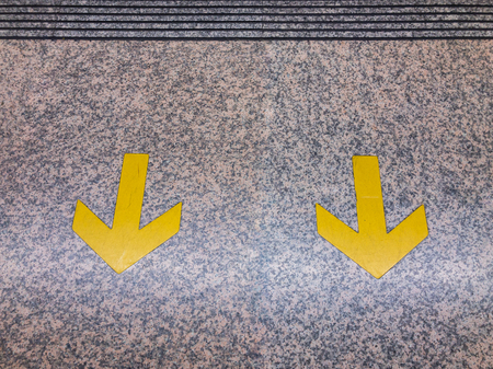 Yellow arrow sign on rail platform close up.の写真素材