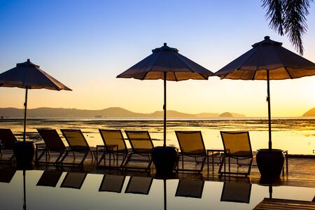Silhouetted picture, the beautiful sunrise at the beach with bed and swimming pool.の写真素材