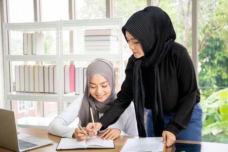Asian Muslim businesswomen talking and working together in the office. Diversity cultural and gender concept.の写真素材