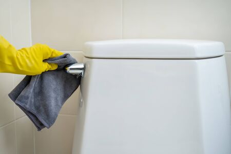 Maid cleaning flush toilet by using alcohol and liquid cleaning solution. Covid-19 protecting...