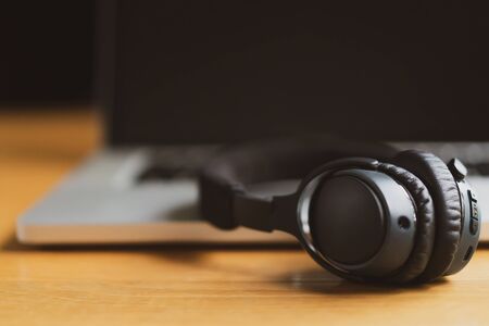 Modern stereo wireless headphones left on the laptop computer with copy space on left side close up....