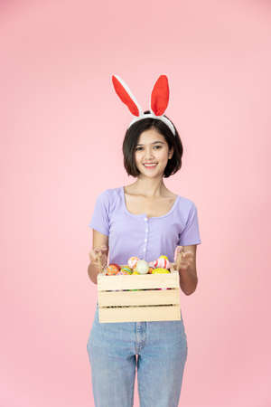 Pretty young Asian woman in Easter egg festival concept on bright pink background. Woman in Easter...