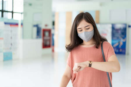 Beautiful Asian business woman walking in the hall during the rush hour and looking at her watch close up with copyspace in left side. Worried Asian businesswoman fast walking in the airport terminal.の写真素材