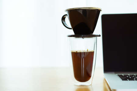 Unrecognizable man making a hand craft dripping coffee on the wooden table in the office during a...