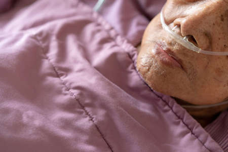 Very old Asian man age between 85 - 90 years old admitted in the hospital, elder man got a critical health problem. Close up at a wrinkled hand old an old man that resting on the bed in hospital.の写真素材