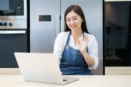 Happy beautiful Asian woman using a video call on laptop computer or notebook to talk with her...