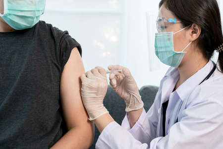 Asian professional doctor injecting a   vaccine at male patient arm close up,  vaccinating about protecting and build antibody - immunityの写真素材