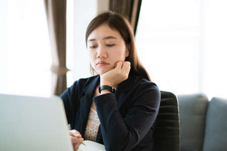 Stressful Asian businesswoman working at the office with suffer and unhappy emotion. Woman feels uncomfortable while working at office, woman suffering about her work. Girl worried for overworking.の写真素材