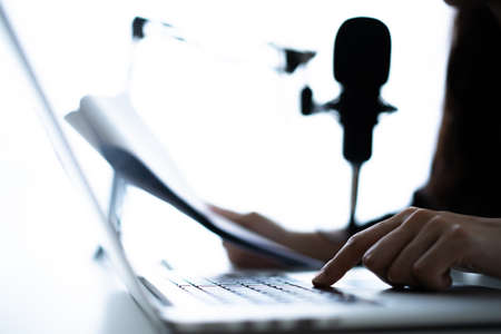 Beautiful and good looking young Asian woman arranging home podcast channel. Businesswoman recording her podcast for her online podcast live on the laptop computer and tablet. Modern working lifestyleの写真素材