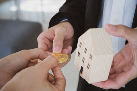 Concept of people using a cryptocurrency or digital currency in real life exchange, unrecognizable people using BTC - bitcoin to purchase their house or other asset.の写真素材