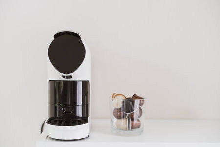Modern coffee capsule machine on the table in the office with copy space. Espresso coffee machine and capsules in container. Aromatic espresso pot and automatic coffee machine.の写真素材