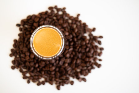 Espresso coffee in a cup surrounding with medium dark roasted coffee beans close up with copy space.の写真素材