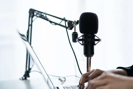 Beautiful and good looking young Asian woman arranging home podcast channel. Businesswoman recording her podcast for her online podcast live on the laptop computer and tablet. Modern working lifestyleの写真素材