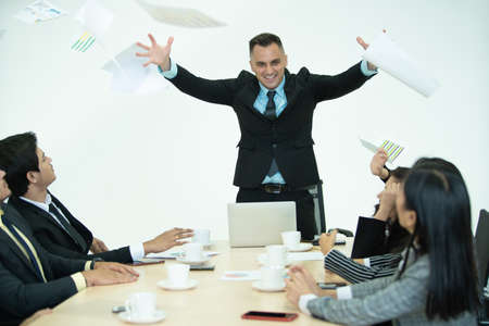 Aggressive businesspeople in meeting, the angry boss throwing a paperwork in the air during business...