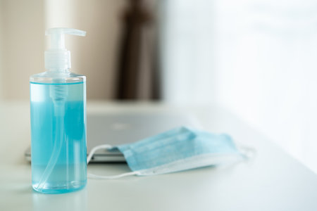 Hygiene protective face mask and laptop computer on the table in home office close up with copyspace. Healthcare and new normal concept in 2019 pandemic.の写真素材