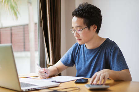 Young Asian businessman in relax casual during working from home. Asian man staying at home and...