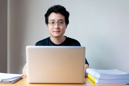 Portrait of Asian young businessman working from home during the quarantine period. Young businessman working at his home in the living room. Work from home during coronavirus disease concept.の写真素材