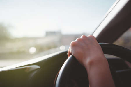 Woman driving a car and catching on the steering wheel at 12 o'clock position with copy space. Woman driving a long the highway during the day, serious driving woman.の写真素材