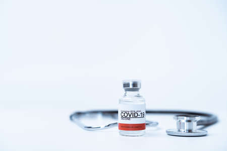 Coronavirus or COVID-19 cure vaccine in a 10 ml. dose for injection use only, COVID-19 vaccination concept and stethoscope close up on white background with copy space . Influenza pandemic 2019.の写真素材