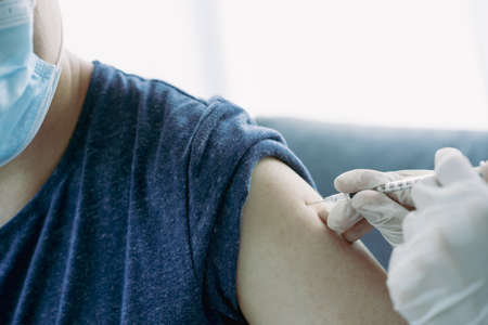 Doctor preparing a dose of vaccine for injection at patient left arm close up with copyspace. Healthcare and medical service concept.の写真素材