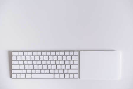 Modern wireless computer keyboard and touchpad on the white table, decorated in minimalist style with copyspace. Modern computer accessories and gadget.の写真素材