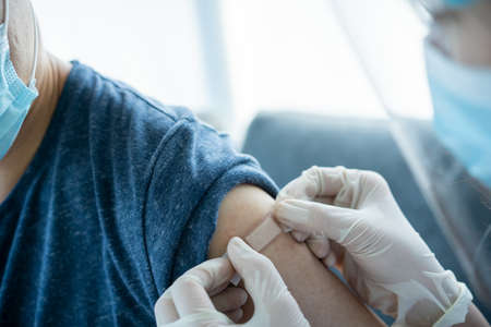 Doctor preparing a dose of vaccine for injection at patient left arm close up with copyspace....