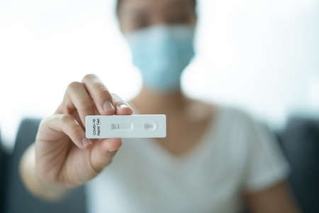 Asian young woman with hygiene protective face mask using  antigen rapid test kit - ag test kit at home.  antigen rapid test.の写真素材