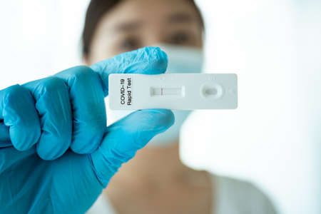 Asian young woman with hygiene protective face mask using  antigen rapid test kit - ag test kit at home.  antigen rapid test.の写真素材