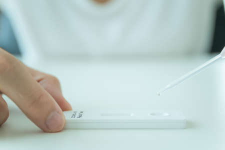 Asian young woman with hygiene protective face mask using SARS 2019-nCoV COVID-19 coronavirus antigen rapid test kit - ag test kit at home. COVID-19 antigen rapid test.の写真素材