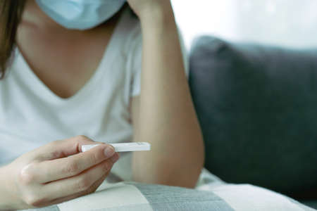 Asian young woman with hygiene protective face mask using SARS 2019-nCoV COVID-19 coronavirus antigen rapid test kit - ag test kit at home. COVID-19 antigen rapid test.の写真素材