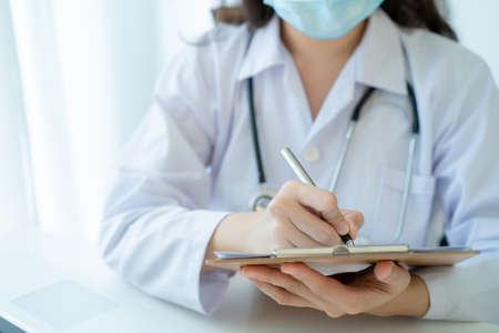 Asian doctor working in the office in hospital and reviewing a medication report close up with copyspace, healthcare worker portrait. Female doctor examine a medication cure diagnostic report.の写真素材