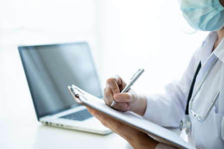 Asian female doctor using laptop computer for working in hospital. Doctor working with laptop - notebook computer in office in hospital. Health care worker and service.の写真素材