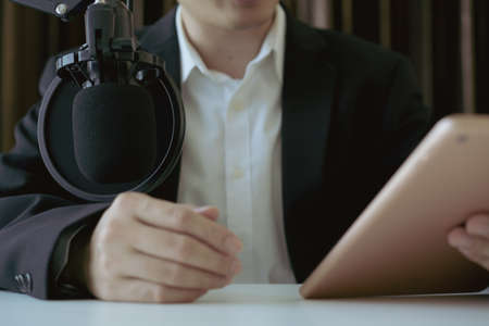 Unrecognizable Asian businessman making his online podcast from home, a businessman talking on the online radio station and using professional condenser microphone. Audio live streaming concept.の写真素材