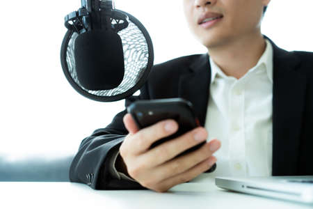 Unrecognizable Asian businessman making his online podcast from home, a businessman talking on the online radio station and using professional condenser microphone. Audio live streaming concept.の写真素材