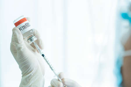 Doctor preparing a dose of vaccine for injection at patient left arm close up with copyspace....