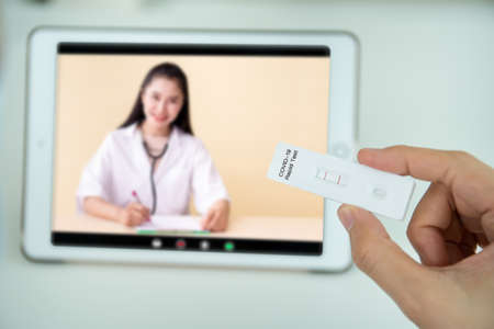 Mockup modern tablet with empty screen isolated with clipping path. Asian young woman using tablet for online video call with a doctor after her COVID-19 antigen testing result was positive.の写真素材