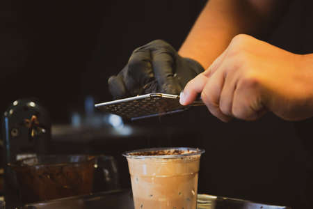 Specialty crafted iced chocolate beverage service on the wooden plate close up. A professional barista brewing a special iced chocolate in the cafe and restaurant.の写真素材