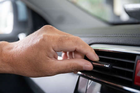 Unrecognizable man adjusting the vehicle air conditioner grille for better air flow, modern vehicle...