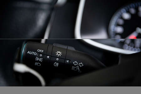 Modern headlight switch in the modern car cockpit close up with copyspace. Automatic vehicle headlight controller stick on the dashboard behind the steering wheelの写真素材
