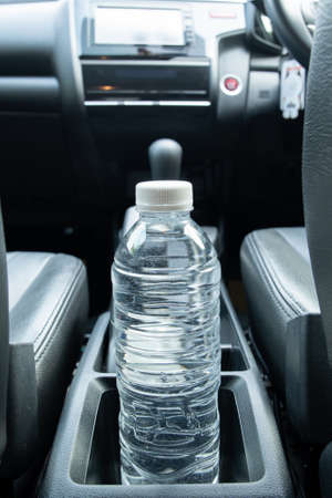 Plastic water bottle left in the vehicle while parking at outdoor carpark, plastic bottle with water...