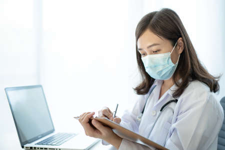 Asian female doctor using laptop computer for working in hospital. Doctor working with laptop - notebook computer in office in hospital. Health care worker and service.の写真素材