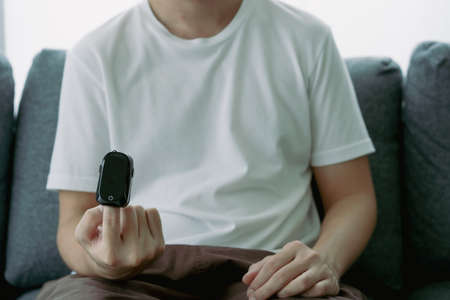 Man using oximeter to measure his blood oxygen saturation and pulse. Digital portable blood oxygen meter.の写真素材