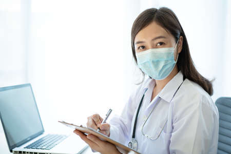 Asian female doctor using laptop computer for working in hospital. Doctor working with laptop - notebook computer in office in hospital. Health care worker and service.の写真素材