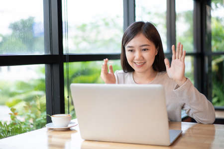Happy Asian woman concentrated working in the coffee shop by using laptop computer. Confident Asian girl use notebook computer for browsing the internet and social network with beautiful smile.の写真素材