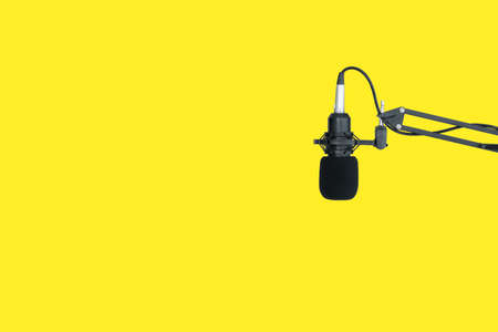 Isolated object with clipping path on bright yellow background. Professional condenser microphone on the microphone holder close up with copyspace. Condenser mic in sound and audio recording studio.の写真素材