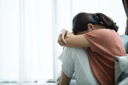 Unhappy Asian young woman having a depressed disorder problem and living alone in living room. Mental health care in young people concept.の写真素材