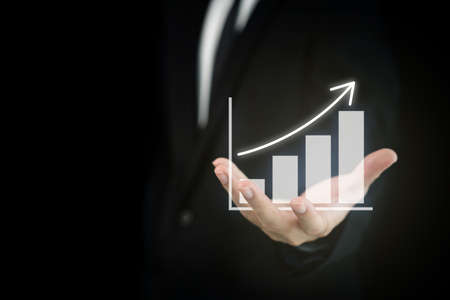 Concept of business and financial growth. Unrecognizable businessman in business smart casual pointing his finger on the graphic chart in business report.の写真素材