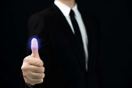 Unrecognizable smart businessman showing his thumb to use fingerprint biometric identification, cyber security concept. Safety connectivity on the internet.の写真素材
