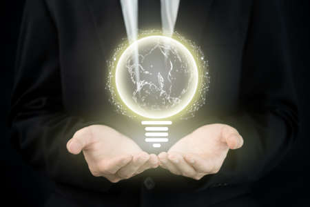 Unrecognizable smart businessman showing an illuminated lightbulb on hand close up with copyspace. Conceptual of globalization and world wide business.の写真素材